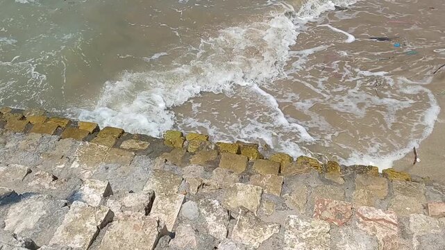 Ocean waves crashing onto a stone-lined shore, a serene coastal scene