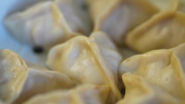 Close-up of steamed khinkali in a white ceramic steamer.