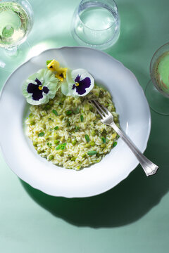 Light green spring risotto with peas and herbs, flowers. Spring menus