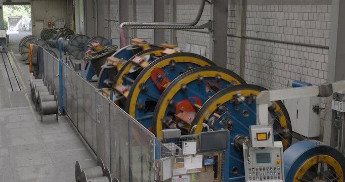 Wide angle view of a large-scale industrial machine for manufacturing steel wire rope in a factory setting