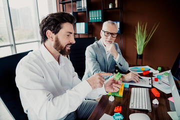 Two colleagues collaborate at a modern office using building blocks to design a project and discuss strategy while exploring ideas and planning a creative business solution © deagreez