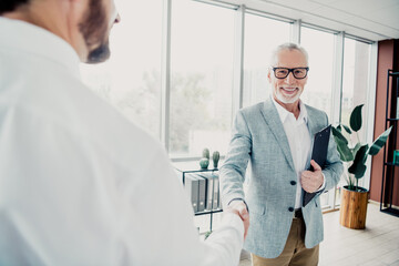 Obraz premium Business handshake in a modern office between senior executive and colleague during a meeting in a bright loft style space