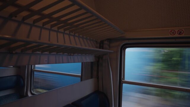 Journey inside a vintage train car compartment revealing the beautiful, fast-moving scenery outside the window. Commuting through the countryside