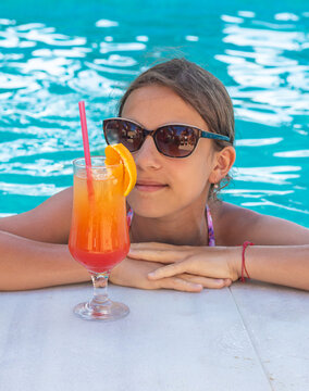 Woman in the pool with a cocktail. Selective focus.