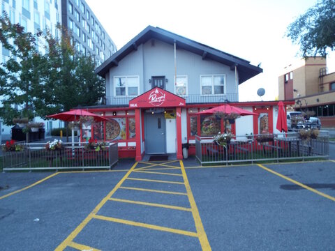 Ottawa, Ontario, Canada &ndash; July 26, 2025: "Royal Shawarma" storefront features a red awning, outdoor patio with red umbrellas, metal railings, and yellow parking lot lines at  704 Brookfield Rd.
