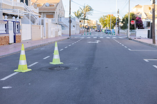 Yellow green cones with a white stripe on the asphalt road. Drive safety and constructions concept.