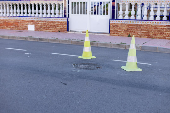 Yellow green cones with a white stripe on the asphalt road. Drive safety and constructions concept.