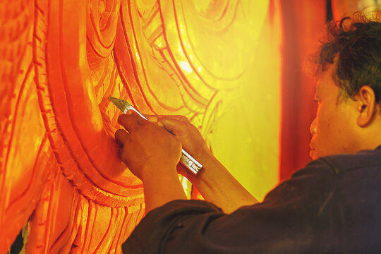 Artist using carving knife to carving candles for candle festival in Thailand.