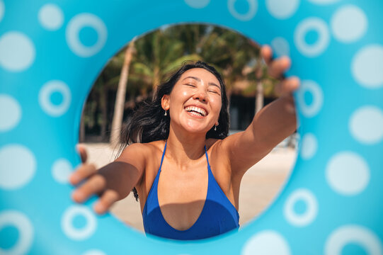 Cheerful woman posing with a blue swim ring on a sunny tropical beach