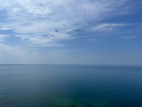 Calm blue sea and sky with clouds.