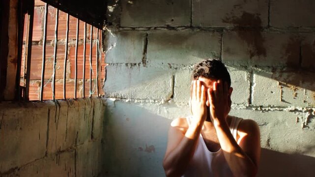 A Hispanic prisoner expresses regret and frustration outside a prison window at sunset in Neiva, Huila, Colombia. Concept of regret and psychology