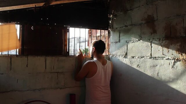 A Colombian prisoner approaches a cell window to watch the sunset inside a prison in Neiva, Huila, Colombia. Concept of frustration and loneliness