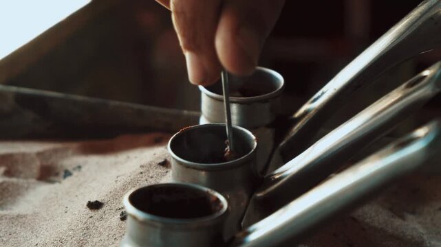 Traditional process of making Turkish coffee in a copper cezve on hot sand. Close-up of brewing coffee with foam rising, authentic oriental preparation method
