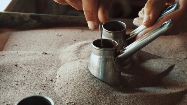Traditional process of making Turkish coffee in a copper cezve on hot sand. Close-up of brewing coffee with foam rising, authentic oriental preparation method