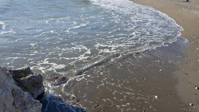 Close-up of waves on a sandy beach along the Mediterranean coast in Malaga, Andalusia, Spain.