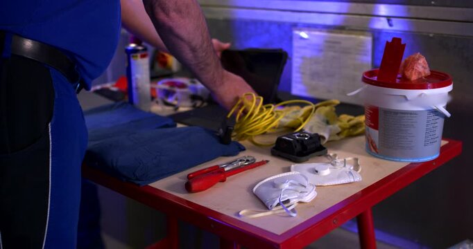 Close up of a worker reaching for personal protective equipment and tools on a workbench in a workshop