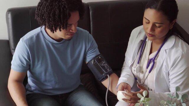 Female doctor visiting a male patient at home and checking his blood pressure with a tonometer