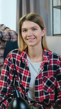 Portrait of woman with long light hair which posing on camera in new apartment while her confident skilful african american man or boyfriend collecting rack using rechargeable screwdriver