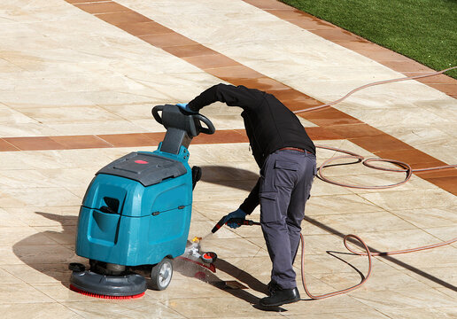 M&aacute;quina limpia suelos aspiradora, barredora, fregadora, pulidora y rotativa con manguera de agua y portero de finca limpiando patio