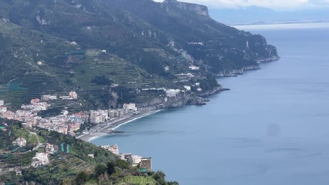 Panoramic view from Ravello over Amalfi Coast with terraced hills, coastal town, and calm blue sea, showcasing iconic Italian landscape and Mediterranean beauty.
