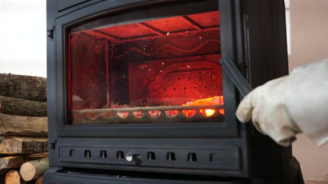 Loading firewood in Burning wood stove. Load firewood into Cast iron fireplace. Putting Firewood Into the Cast iron stove in home. Heating your home in cold weather with a wood stove. Wood logs stacke