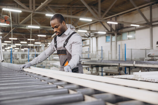 Factory worker handling PVC window profile on production line