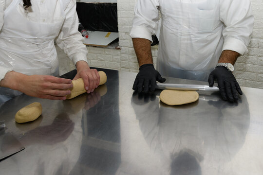 Workers at a Jerusalem matzah bakery use metal rolling pins to flatten chunks of dough into round sheets of matzah prior to baking the unleavened bread for the Jewish holiday of Passover in Israel.