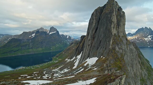 Hyperlapse of Segla mountain towering above fjord in Senja, Norway. Dramatic sharp rock peak with snow patches, deep blue water, and remote village below. Iconic Arctic landscape with rugged Nordic.