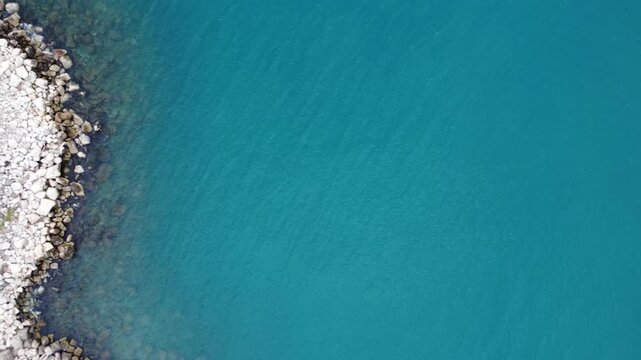 Aerial vertical shot of jetty with visible seabed and calm ripples