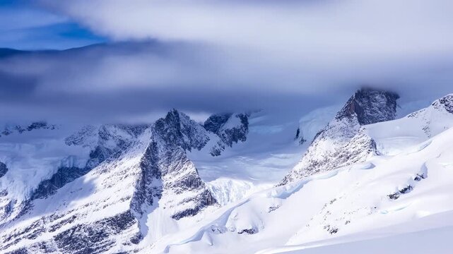 Alpine Landscape With Icy Summits. Snowcapped Mountain Range Under Clear Blue Sky With Rugged Ridges
