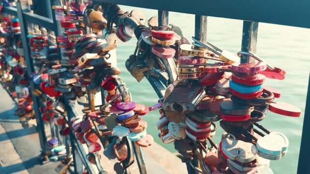 Colorful love locks symbolizing everlasting romantic commitment and unity, securely fastened to a bridge railing with many couples adding their personalized padlocks over a river