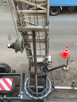 From above, professional furniture hoist base assembly with hydraulic supports on urban asphalt.