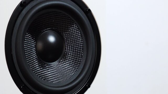 Close-up shot of a black speaker woofer with visible vibration and texture detail. Concept of sound, music, audio technology, bass, and modern sound systems. Minimal background with copy space