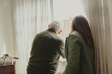 Obraz premium Senior man and adult daughter looking out window