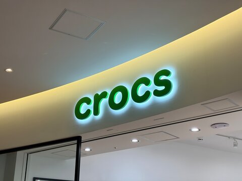 Crocs storefront logo and signage with green illuminated letters at a shopping mall near Godiva boutique in Koto ward - Tokyo, Japan, February 4, 2026