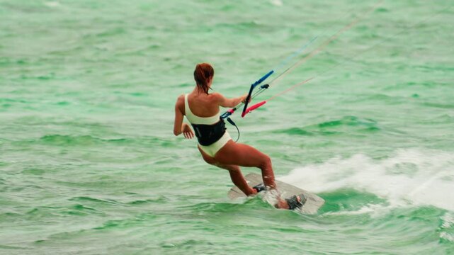 Sports woman kitesurfing in ocean in white bikini. Extreme summer sports