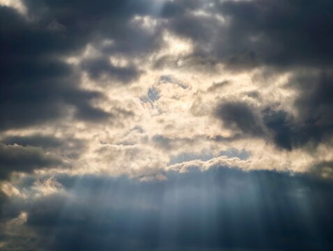 Sun rays cut through dark skies. Intense sunlight pierces ominous stormy cloud formations dramatically