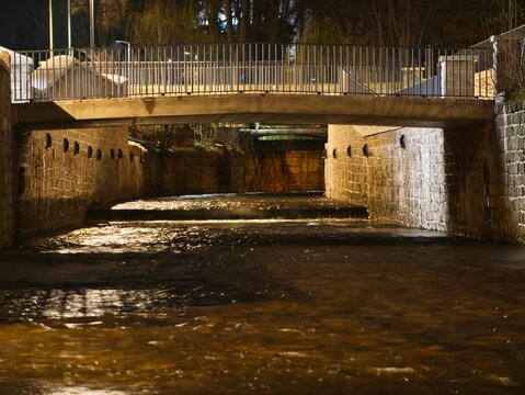 Gloomy riverside scene. Quiet city underpass illuminated by amber reflections and shadowed archways