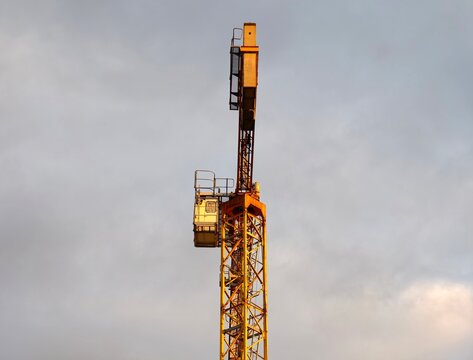 Industrial crane scene. Sunset illuminates urban construction. Dusk highlights towering metal structure