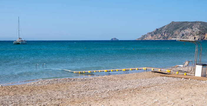 Accessible beach pathway with floating platform and handrails extending into blue sea, Chios island, Greece