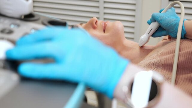 Doctor performing ultrasound examination of neck using medical equipment in clinic diagnostic imaging of thyroid and soft tissues healthcare concept.