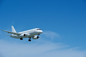 Obraz premium Commercial White Jet on Final Approach, Blue Sky with Light Clouds, Copy Space.