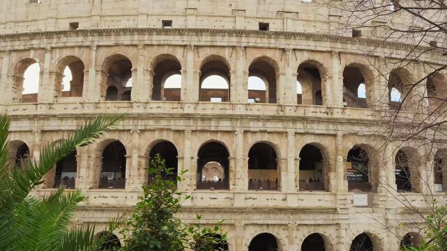 Ancient Colosseum wall in Rome with rhythmic rows of arches and visible aging on the stone surface. Symbol of ancient Roman architecture and history
