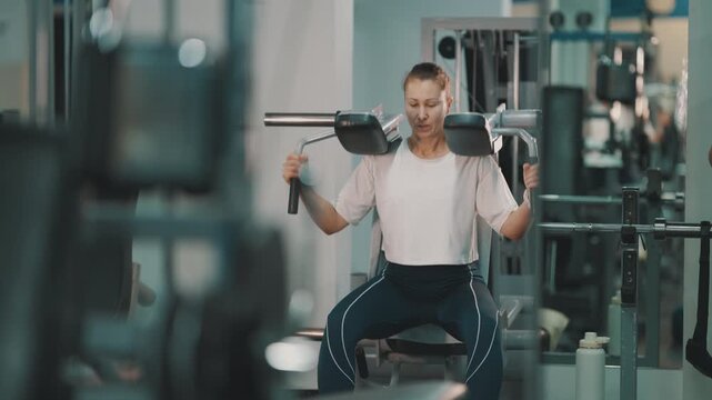 Determined woman performing squats on a hack squat machine