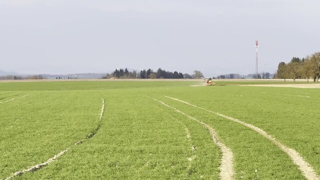 tractor harrowing agricultural field in spring