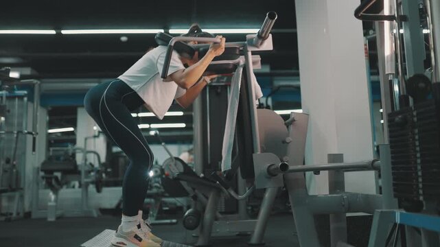Woman performing leg day squats on machine at the gym