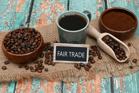 Coffee beans, powder and a cup of coffee with a Fairtrade sign on a rustic background.
