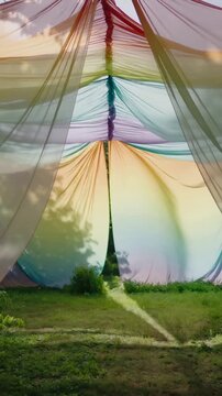 Vertical video: Billowing rainbow canopy shifting in garden, revealing slit seam and sun patch