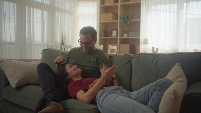 Cozy intimate moment at home with wife resting in her husband&rsquo;s lap on the couch, sharing love and warmth
