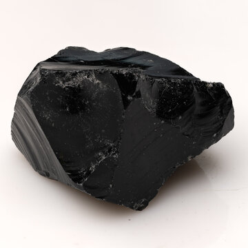 Polished Black Obsidian Volcanic Glass Rock with Sharp Conchoidal Fractures and Glossy Texture on White Background.